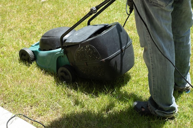 Grasmaaier tas en werknemer man snijden het gras in de tuin.