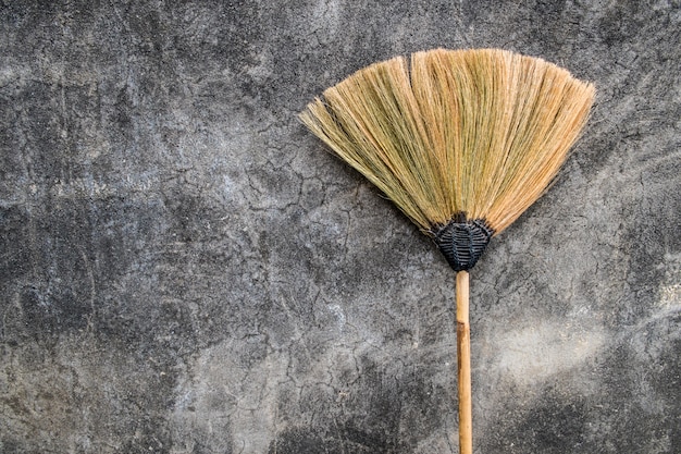 Photo a grass broom lay against the old cement wall.