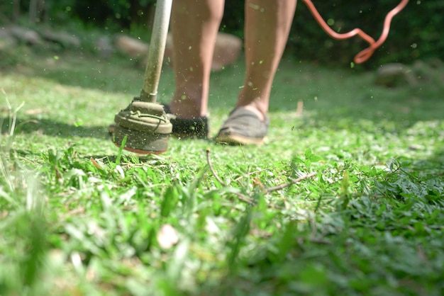 전기 잔디 트리머를 사용하여 잔디를 깎는 잔디 깎는 남자