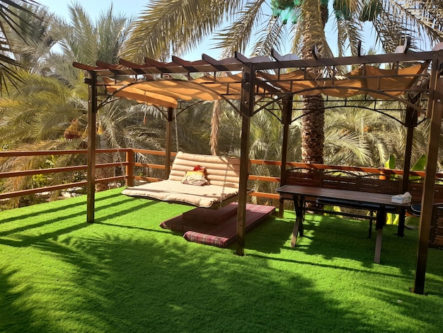 A grassy area with a wooden canopy and a table and chairs.