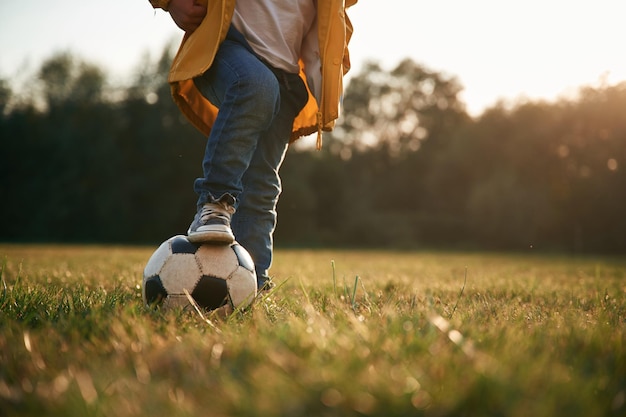Photo grassy ground with soccer ball little boy is playing outdoors at daytime