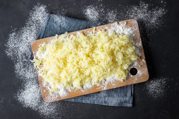 Grated boiled potatoes with flour for the preparation of an Italian dish - potato gnocchi. Black background.