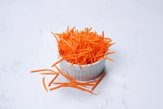 grated carrot in a bowl on white background