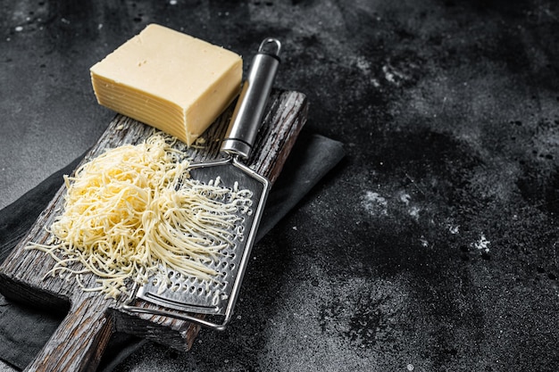 Grated cheese for cooking on a cutting board Black background Top view copy space