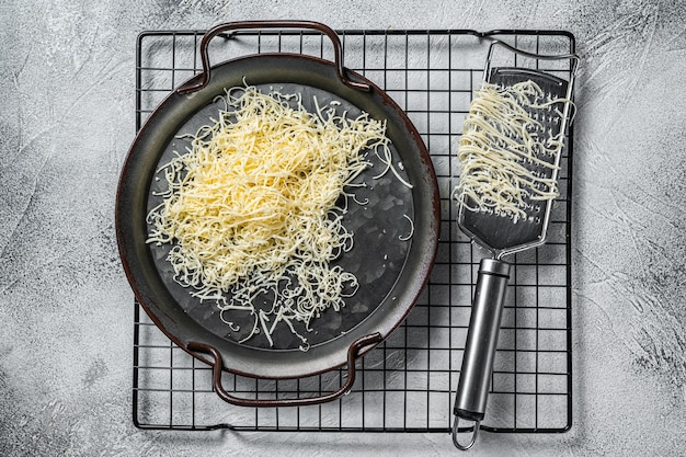 Grated cheese for cooking in a steel tray with grater White background Top view