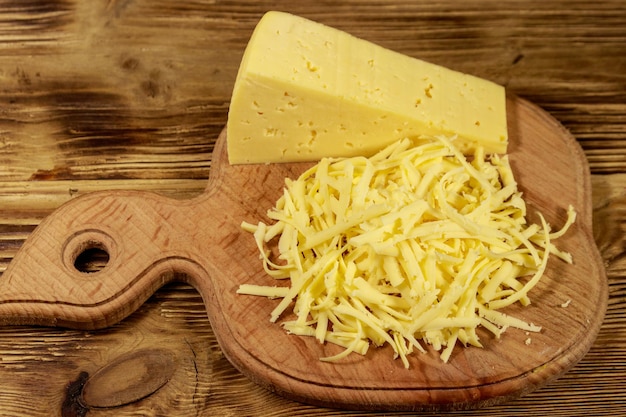 Grated cheese on cutting board on wooden table