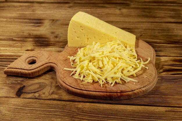 Grated cheese on cutting board on wooden table