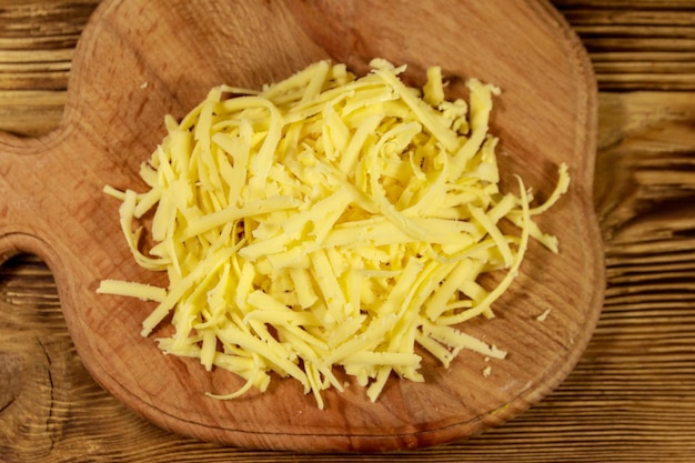 Photo grated cheese on cutting board on wooden table