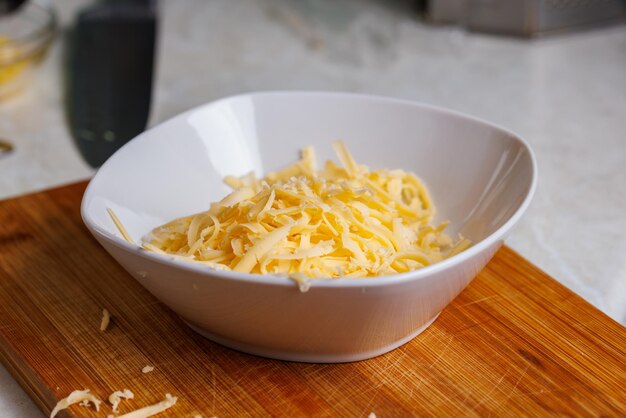 Grated cheese in white ceramic bowl close-up view with selective focus