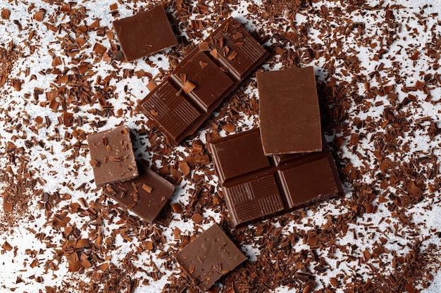 テーブルの上でグレーテッドチョコレートと美味しいチョコロートの塊