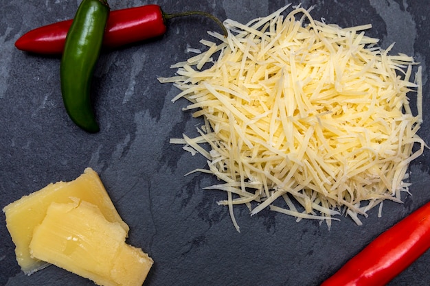 Grated Parmesan cheese on black stone with garlic, onion, pepper and other spices