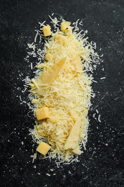 Grated parmesan cheese cheese top view on a black stone
background