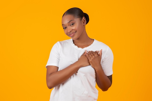 Grateful african american young lady pressing hands to chest studio