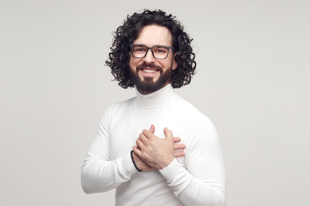 Uomo felice grato che tiene la mano sul petto in studio