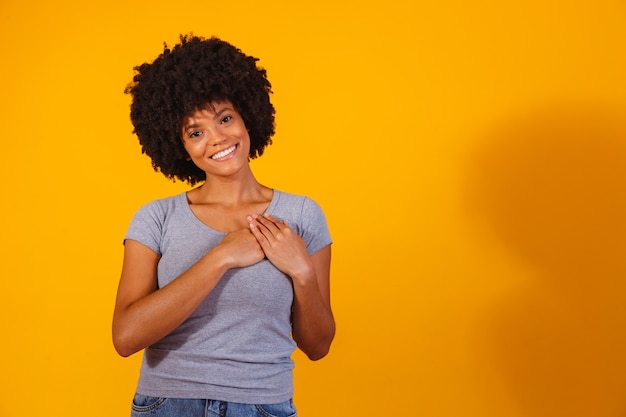 Grateful hopeful happy black woman holding hands on chest feeling pleased thankful