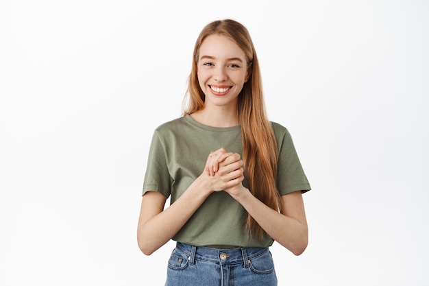 Grateful smiling blond woman, say thank you, appreciate help, looking thankful and pleased, shaking clenched hands to show her support, united we stand, standing over white background
