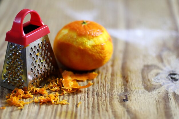 Grater zest of citrus fruit and on the wooden table