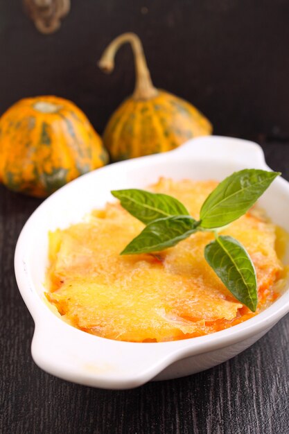 Gratin potatoes and pumpkin with milk in a black background