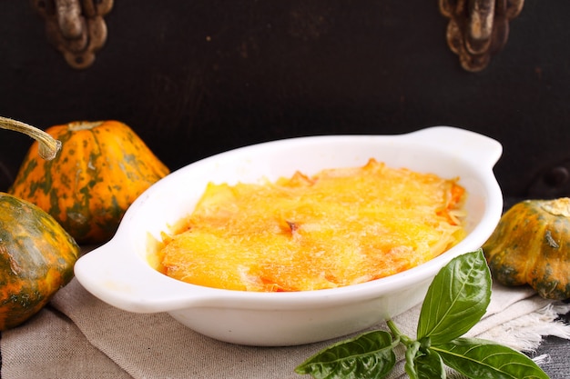 Gratin potatoes and pumpkin with milk in a black background