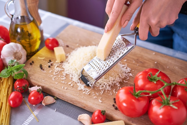 Grating parmesan on a wooden gutting board at domestic kitchen