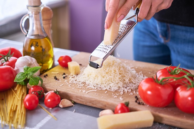 Grating parmesan on a wooden gutting board at domestic kitchen