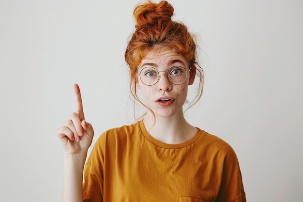 Foto gratis binnenfoto van een positieve persoon in een casual rood t-shirt met wijsvinger opzij