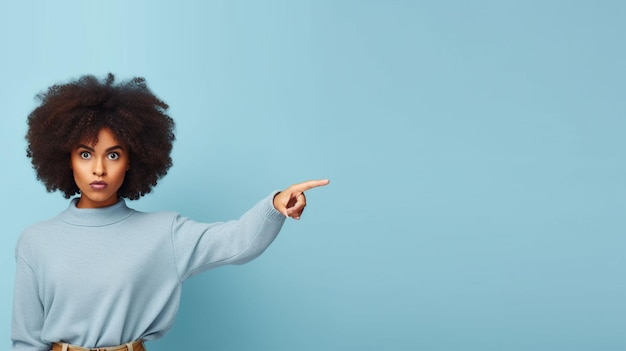 Gratis foto jonge vrouw die met haar vinger naar de zijkant wijst over een geïsoleerde blauwe muur