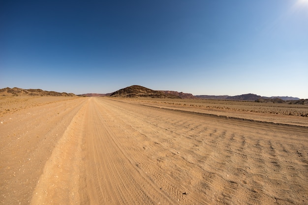 Gravel 4x4 road crossing the colorful desert at Twyfelfontein, in the majestic Damaraland Brandberg, scenic travel destination in Namibia, Africa.