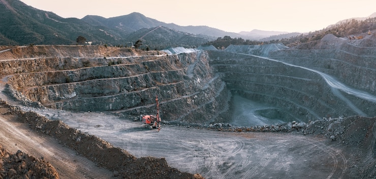 Photo gravel quarry with terraces piles of stone and red crusher machine with mountains background
