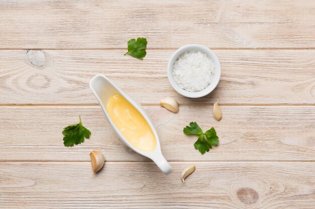 Gravy boat with tasty cheese sauce on table background top view