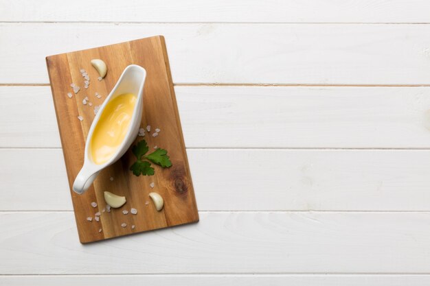 Gravy boat with tasty cheese sauce on table background top view