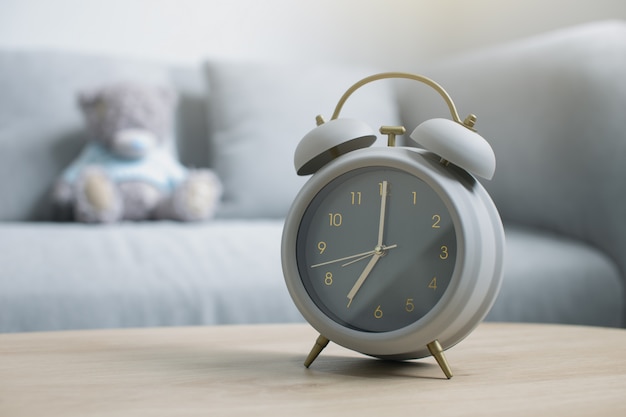 Gray alarm clock on a wooden table in the morning light at the living room