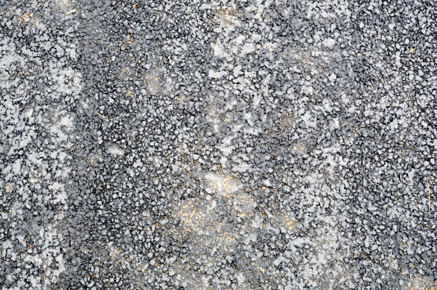Gray asphalt road with small pebbles and cracks Texture background
