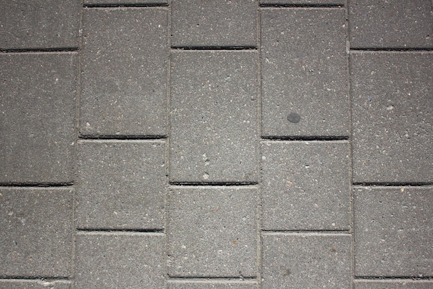 Gray background of a brick pavementBackground of a block of gray stone tiles Surface of a gray brickStone pavement slab texture Roadtileconcrete slab