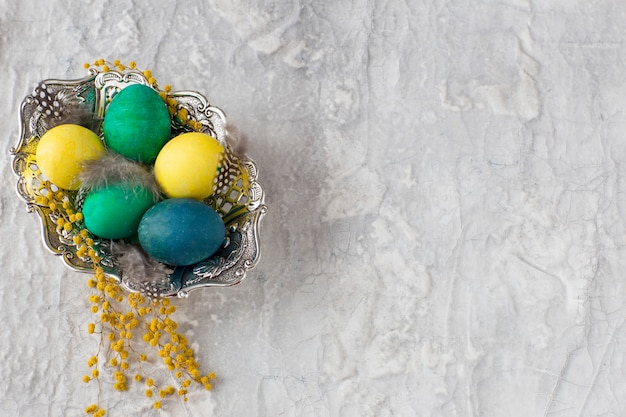 회색 배경에 페인트 계란, 미모사-부활절 배경으로 오래 된 접시.