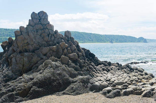 Rocce di basalto grigio contro un paesaggio marino costiero sfocato