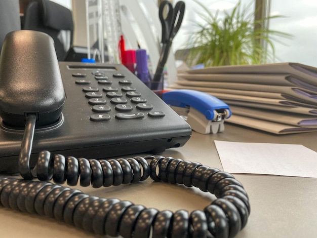 Photo gray and black business wired phone with receiver dial and large display in the business office environment