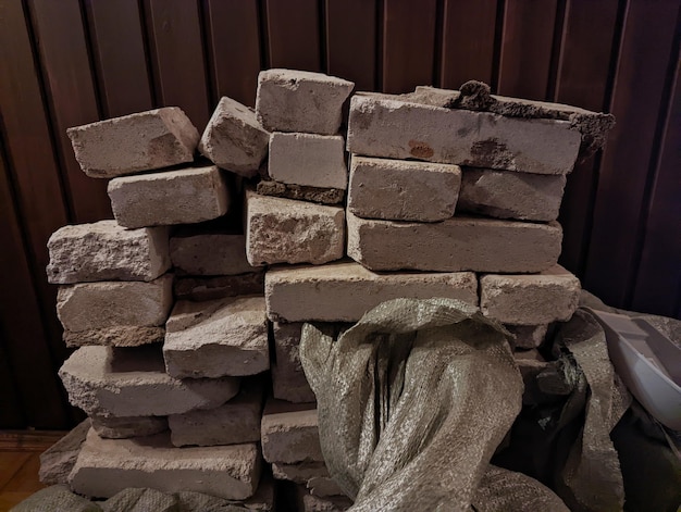 gray bricks and construction debris stand near a wooden brown mesh