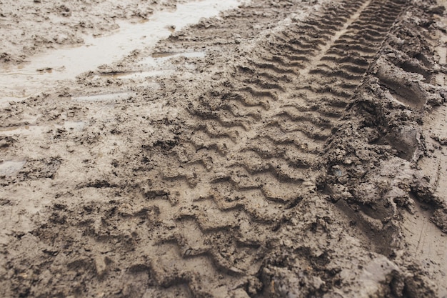 도로의 젖은 진흙과 땅의 자동차 흔적에서 나온 회색 갈색 질감