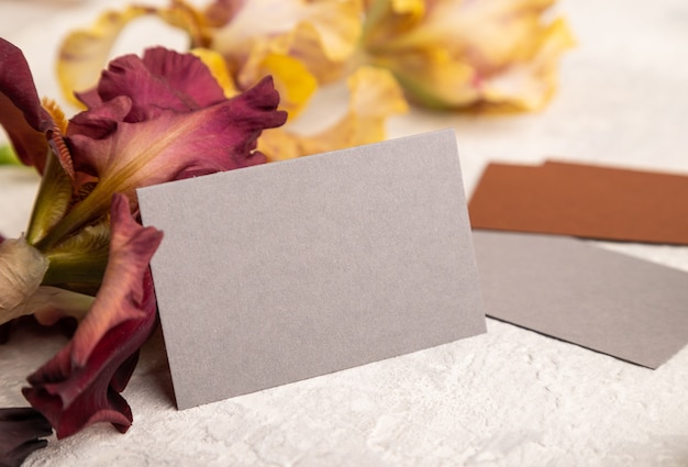 Gray business card with iris flowers on gray concrete background. side view, copy space, still life.