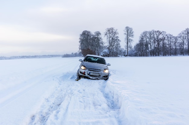 Un'auto grigia si è schiantata su una strada scivolosa e innevata in una giornata invernale.