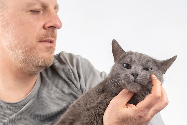 Gatto grigio che si siede sul petto dell'uomo