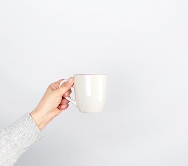 Gray ceramic cup in female hand on white 