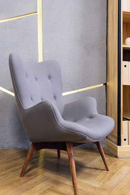 Gray chair upholstered with textiles with wooden legs in a modern office interior