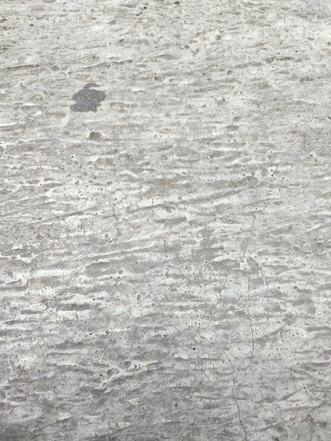 a gray concrete surface with a white texture that has a small black spot on it