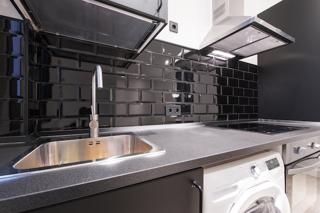 Gray countertop with stainless steel sink black tiles and black wood cabinets