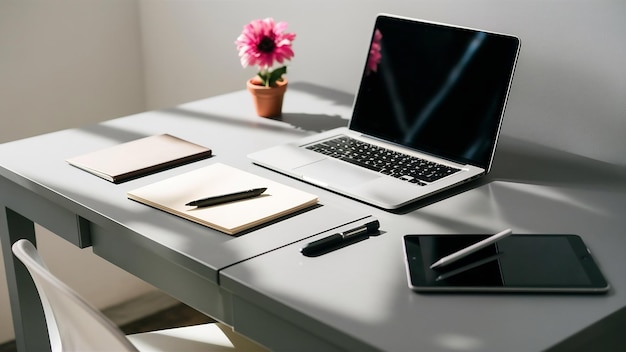 The gray desk with laptop notepad with blank sheet pot of flower stylus and tablet for retouchin