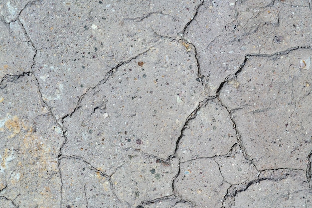 Gray dry cracked surface of volcanic soil turned into desert. Natural background or texture taken in environment in crater of active volcano. Concept: global warming, drought soil erosion.