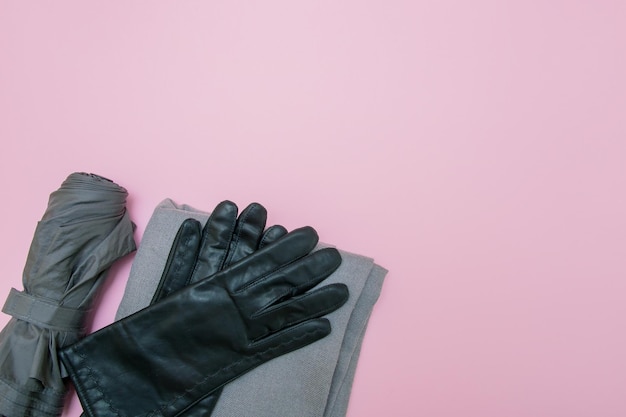 Photo gray gloves umbrella and scarf on a pink background with copy space