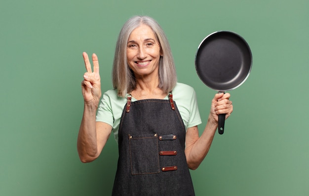 Gray hair pretty middle age chef woman with a pan